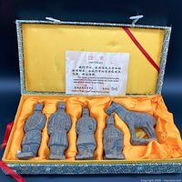 Miniature replica set of four terracotta soldiers and one horse displayed inside a decorative fabric box lined with orange satin and accompanied by a certificate.