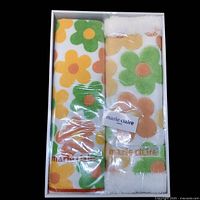 Packaged floral print bathroom rug and towel set with green, orange, yellow flowers and Marie Claire branding