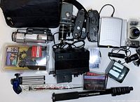 Photo showing the variety of items including cameras, bag, tripods, tapes, and accessories spread on flat surface
