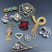 Overview photo of the full lot showing 11 assorted rhinestone brooches on black background.