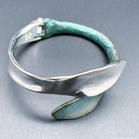 View of the hinged bangle bracelet showing the sculptural petal design with patina and silver finishes.