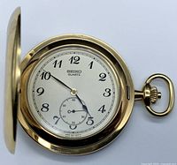 Open-face view showing white dial, Arabic numerals and subsidiary seconds with gold-plated case.