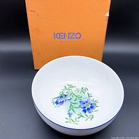 Front view of the Kenzo Maison porcelain salad bowl with visible floral pattern inside and orange Kenzo Maison branded box behind it.