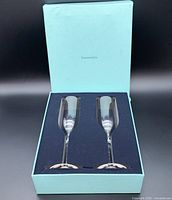 Blue Tiffany & Co. box opened showing two clear champagne flutes nestled in a dark blue insert.