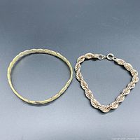 Two pieces of 925 sterling silver bracelets: a braided bangle and a braided chain bracelet with clasp, displayed on a black background.