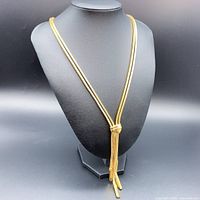 Necklace on bust form showing double chain and central knot with fringe