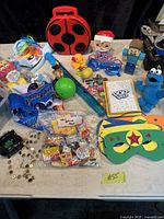 Overview of various kids toys including masks, figurines, plush toys, and novelty items arranged on a surface.