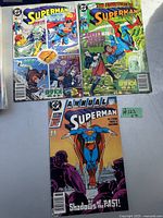 Photo showing three Superman comic books laid out: one titled Superman with snowy fight scene, one The Adventures of Superman #123, and one Superman Annual titled Shadows of the Past.