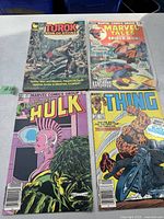 Photo shows 4 vintage Marvel comic books with cover titles: Turok Son of Stone, Marvel Tales featuring Spider-Man, The Incredible Hulk, and The Thing. Comics show normal age wear and creasing.