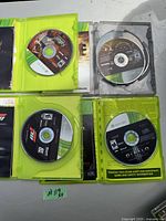 Top view showing four Xbox 360 game discs inside cases with some manual and inserts visible for each game.