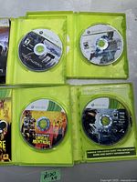 Four Xbox 360 game discs inside original green Xbox 360 game cases, showing front artwork of the discs: Ghost Recon Advanced Warfighter 2, Call of Duty 4: Modern Warfare, Undead Nightmare, and Halo 3 ODST.