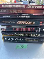 Seven books stacked showing titles and authors on spines.