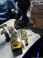 Photo showing various Stanley hand tools including hammers, screwdrivers, tape measure, and utility knife stitched on a surface outdoors.