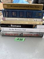 Stack of 8 miscellaneous books showing titles and authors on front spines.