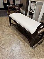 Full angle photo of the solid wood bench with upholstered seat showing the overall structure and finish.