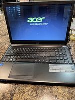 Laptop powered on, showing Acer boot screen and logo.