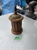 Photo showing front and side view of the antique coffee grinder with wooden fluted body and metal domed top with crank handle.