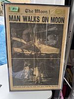 Framed 1969 newspaper showing headline 'Man Walks on Moon' with images of moon landing and astronaut.