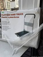 Photo of the platform hand truck in its packaging, showing product image and description including 250 lb load capacity and handle features.