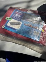 Full packaged air mattress in original red plastic bag with product label showing usage and features.
