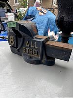 Side view of vintage heavy duty bench vise showing '6' and 'ALL STEEL' in gold lettering on black body.