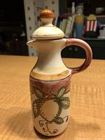 Front side view of stoneware oil pitcher showing lemon motif and handle