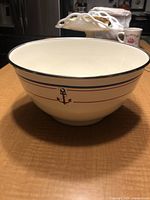 Front angled view of the enamel mixing bowl with anchor design, showing cream enamel with red and blue stripes and anchor emblem.