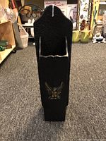 Front angled view of the black iron match holder showing its narrow shape and eagle emblem on the front.