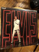 Front cover of Elvis vinyl album with iconic image of Elvis Presley in white suit with large red 'ELVIS' sign behind.