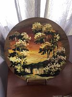 Photo of 12 inch round wood platter with a scenic hand painted nature design, showing cracks on the surface.