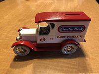 Side front view of vintage Country Fresh Dairy Products truck bank showing branding and coin slot on roof.