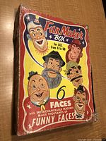 Front side of vintage Fun Maker Box showing 6 cartoon faces and text stating '6 faces with interchangeable features make thousands of funny faces'. Colorful, worn box.
