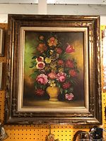 Frontal view of the vintage floral oil painting showing the colorful bouquet and ornate frame with distressed gold accents.