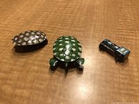 Photo of two tin turtle back toys and miniature tin locomotive arranged on a wooden surface.