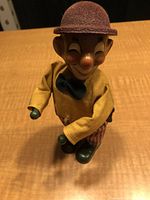 Front view of the vintage wind-up clown figurine showing the full body and outfit on wooden surface.