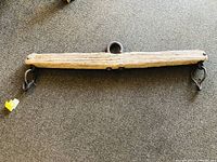 Full view of the vintage wooden yoke with two metal hooks and central ring on the carpet