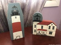 Front and side view of two painted wooden lighthouses, including a tall Sankaty Head lighthouse and a Whidbey Island lighthouse with keeper house.