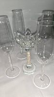 Four clear crystal champagne flutes and one Swarovski crystal candlestick with floral design and textured stem.