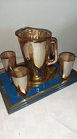 Set of amber/gold lustre Depression glass with jug, four glasses, on a deco tray