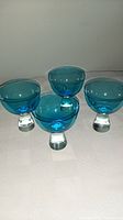 Four blue crystal cocktail glasses arranged in square formation
