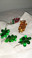 Four handblown Venetian glass ornaments in the shape of grapes and leaves, displayed on white cloth background.