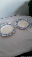 Two blue Willow pattern ceramic dishes with gold rim on white fabric background