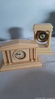 Both ivory-colored French mantel clocks on table, showing overall condition and design
