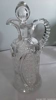 Front left angle view of the clear crystal decanter showing stopper, handle, and detailed cut glass designs.