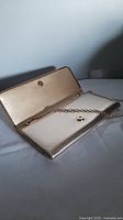 Open purse showing interior with a gold chain strap and snap button closure