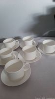 Six white Wedgwood bone china coffee/tea cups with matching saucers arranged on a flat surface.