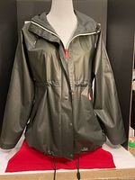 Front view of olive green lightweight Hunter raincoat on mannequin showing button snap front, adjustable hood, and drawcord waist.
