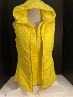 Front view of bright yellow sleeveless vest with zipper and attached removable hood displayed on mannequin.
