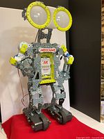 Front angled view of Meccano Meccanoid G15 robot showing large eyes, chest branding, articulated arms, and tank treads.