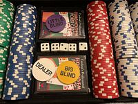Full poker chip set showing chips in various colors, two decks of cards, dealer and blind buttons, and five dice arranged in the carrying case.